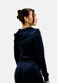 Navy velvet hoodie with a subtle pattern, featuring a drawstring hood, long sleeves, and a fitted design, paired with matching pants.