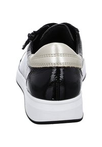 Baskets noir et blanc avec une finition brillante, présentant un accent argent métallique sur le talon et une tige texturée, conçues pour le confort.