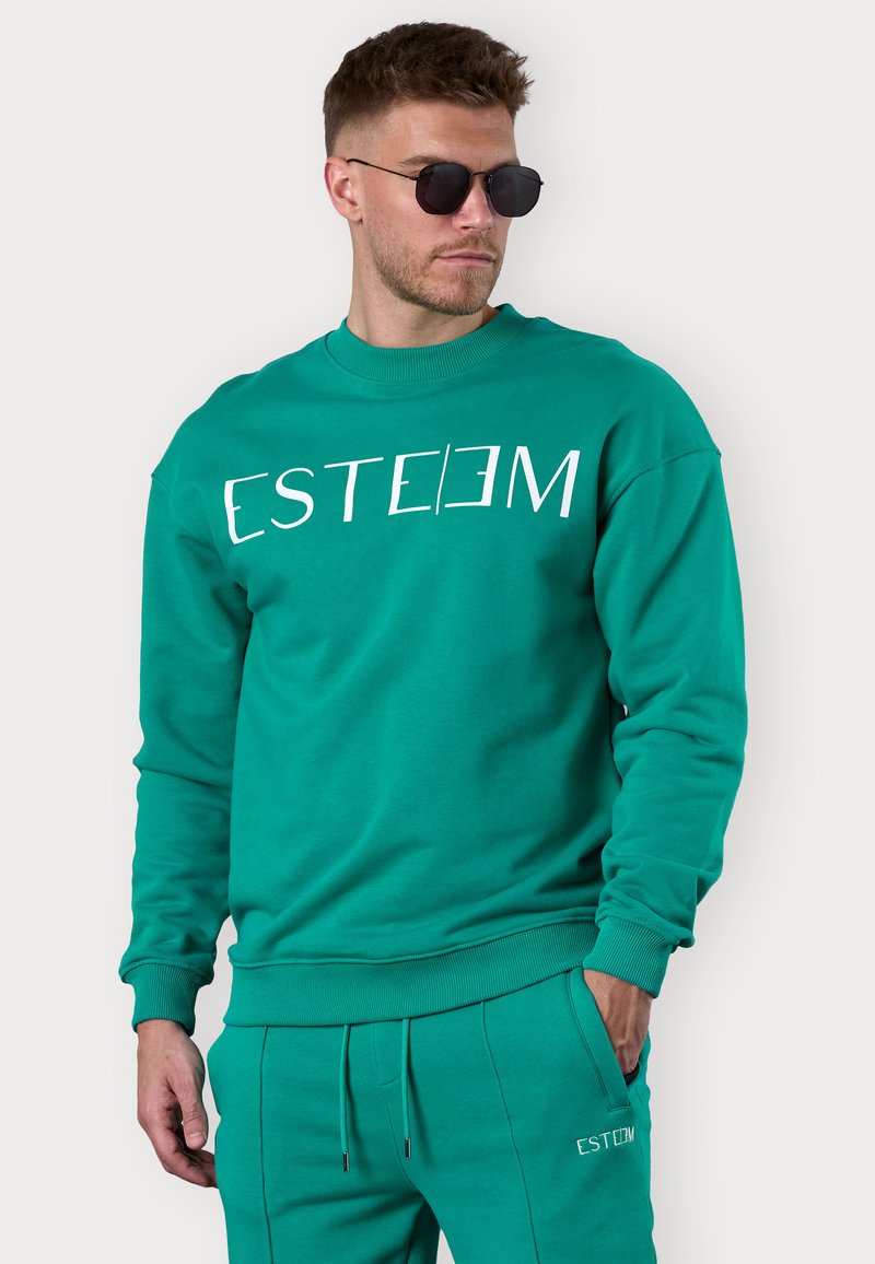 Green sweatshirt with crew neck, ribbed cuffs, and hem. Printed "ESTEEM" logo in white across the chest. Soft, textured material.