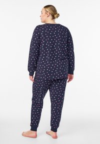 Navy pyjam set met lange mouwen en broek, versierd met kleine roze en witte hartpatronen, gemaakt van zachte, comfortabele stof.