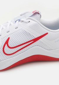 Chaussure de sport blanche avec logo Nike rouge, empeigne en maille, lacets blancs et semelle texturée rouge.