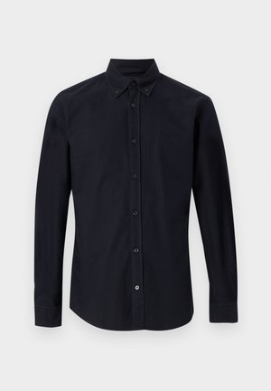 Μαύρο πουκάμισο με μακριά μανίκια, κουμπιά, μυτερό γιακά και διακριτικό κεντημένο λογότυπο στο αριστερό στήθος, εμφανιζόμενο σε απλό φόντο.