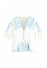 Blusa bianca con ricami floreali blu, scollatura a V, maniche puff e chiusura a fiocco davanti. Dettaglio dell'orlo scallop.