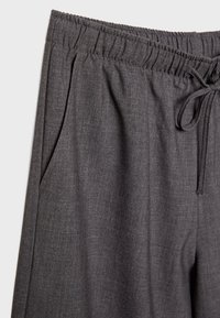 Gray lounge pants featuring an elastic waistband with a drawstring, side pockets, and a soft textured fabric.