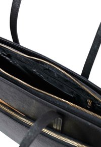 Borsa a mano in pelle nera con esterno testurizzato, zip dorata e due scomparti interni. Spallacci regolabili per un trasporto versatile.