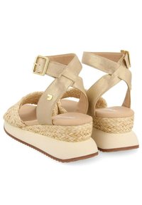 Sandali in pelle dorata con una piattaforma intrecciata beige, cinturini alla caviglia con fibbia e una soletta imbottita per il confort.