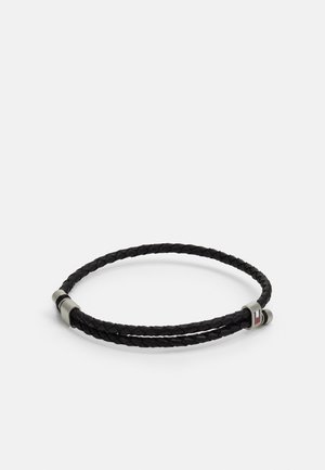 Sorte flettede læderarmbånd med dobbelte strenge og en metallisk lås med en lille logo detalje i rød, hvid og blå nuance.