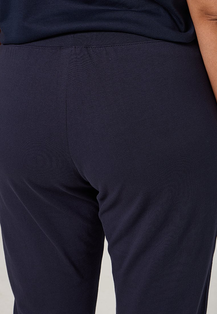 Pantalons extensibles bleu marine avec une texture lisse et une taille élastique, arborant un design ajusté et un style minimaliste.