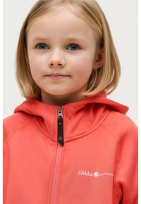 Koraalkleurige fleecejack met een ritssluiting aan de voorkant, een vaste capuchon en een wit logo. Het heeft een soepele textuur en elastische manchetten.