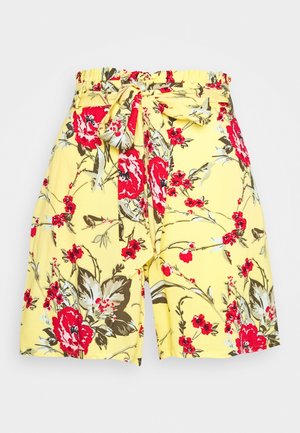 Shorts amarillos de talle alto con estampado floral rojo y marrón y cinturón de tela a juego anudado en un lazo en la parte delantera.