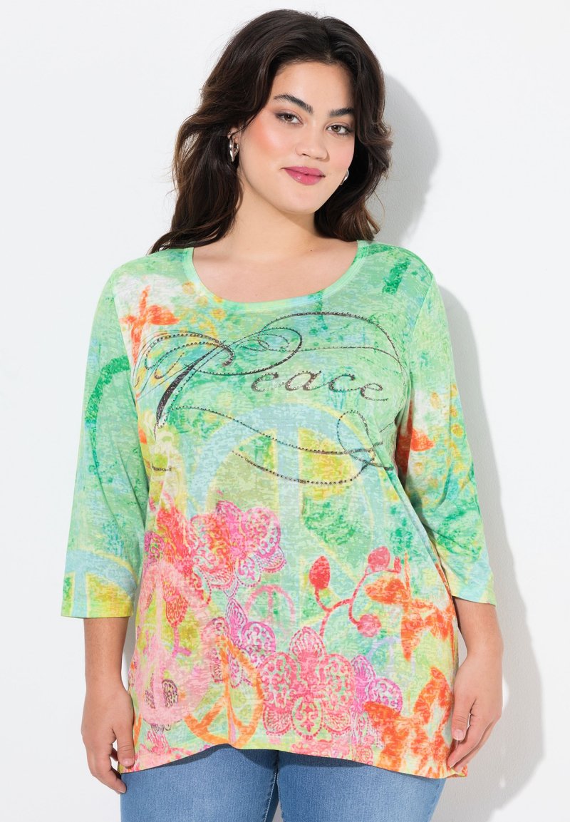 Farbiger, leichter Langarm-Top in Grün mit floralen Mustern, ausgestattet mit orangefarbenen und rosafarbenen Akzenten. "Frieden"-Text mit dekorativen Nähten.
