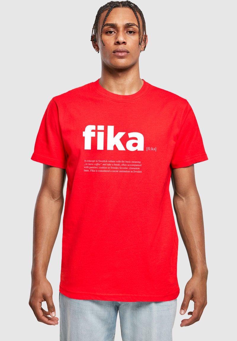 Röd bomull t-shirt med ordet "fika" i fetvita bokstäver och en beskrivning av konceptet nedanför. Rund halsringning och korta ärmar.