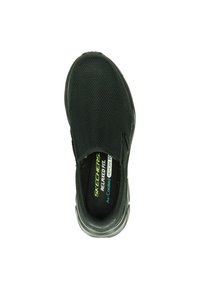 Svart slip-on sko från Skechers, med en texturerad överdel och dämpad innersula, med synliga etiketter för "Relaxed Fit" och "Air-cooled Memory Foam".