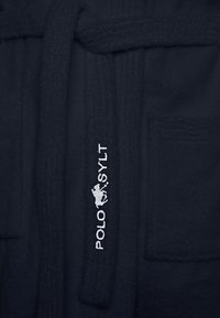 Navy bathrobe made of soft, textured fabric, featuring a tie belt and pockets. Includes embroidered logo in silver.