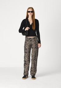 Crna rebrasta majica dugih rukava u kombinaciji s rastezljivim hlačama s leopard printom. Dodatak čini mala crna torbica i tamne sunčane naočale.