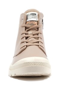 Baskets montantes beiges en cuir lisse, avec un bout rond, des œillets renforcés et une semelle en caoutchouc blanc texturé. Présente un logo de la marque sur la languette.