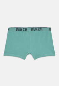 Culottes turquoise avec ceinture élastique noire comportant le texte "BENCH" répété en lettres majuscules.