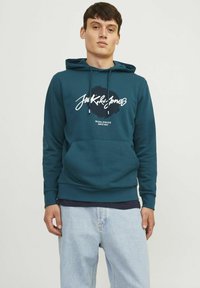 Sudadera de algodón color teal con un gran logotipo en blanco y negro en el frente, que cuenta con un bolsillo tipo canguro y cordones en la capucha.