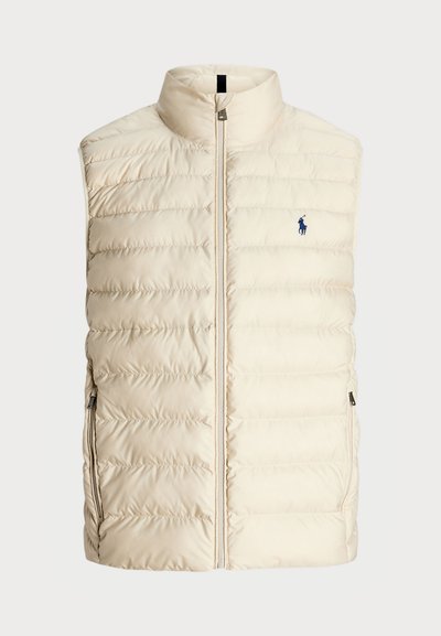 Krekls ar apkakli un krēma krāsas pūkains vests ar kvadrātveida struktūru, priekšējo rāvējslēdzēju un sānu kabatām. Neliels zils logo kreisajā krūtīs.