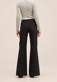 Czarne, rozszerzane spodnie o gładkiej fakturze z dwoma tylnymi kieszeniami, zestawione z jasnoszarym, prążkowanym, długim rękawem.