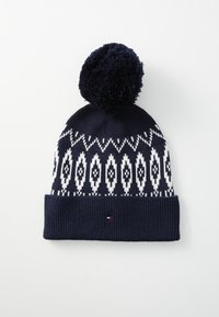 Bonnet en tricot bleu marine avec un motif géométrique blanc, doté d'un revers côtelé texturé et d'un pompon duveteux sur le dessus. Détail de petit logo inclus.