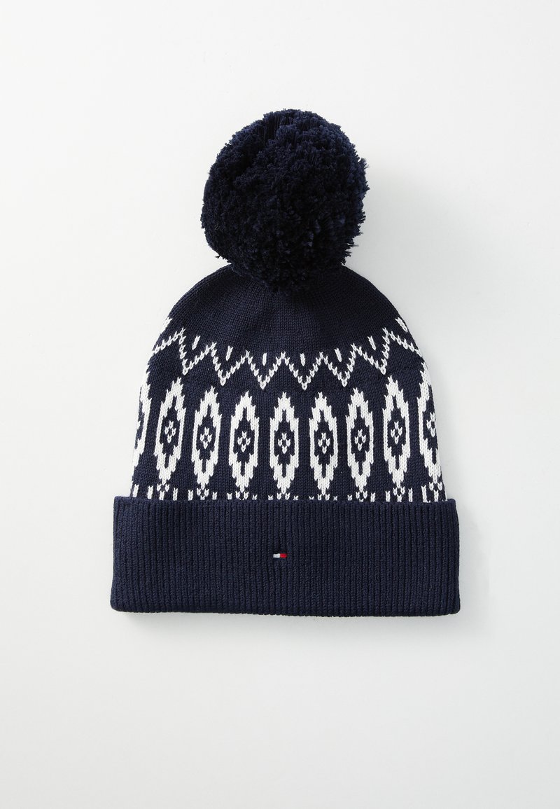 Bonnet en tricot bleu marine avec un motif géométrique blanc, doté d'un revers côtelé texturé et d'un pompon duveteux sur le dessus. Détail de petit logo inclus.