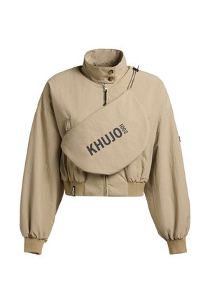 Jachetă bej scurtă, cu guler înalt, manșete elastice, fermoar frontal și buzunar diagonal mare pe piept, inscripționat cu "KHUJO 2001".
