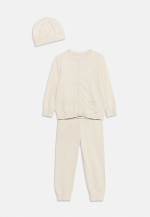 Kreukkleurige gebreide babyoutfit inclusief een langemeurig gebreid vest met knopen, bijpassende broek en een muts op een witte achtergrond.