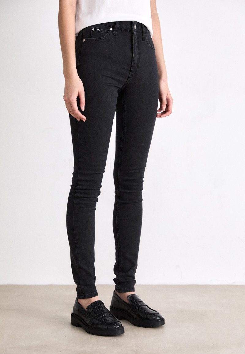 Zwarte skinny jeans van denim, met een gladde textuur, een strakke pasvorm en voorzakken. Draagt met zwarte textured loafers.