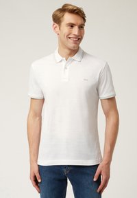 Polo shirt bianco con una patta a tre bottoni, rifiniture grigie a contrasto sul colletto e sulle maniche, realizzato in un morbido misto cotone, dalla forma aderente.