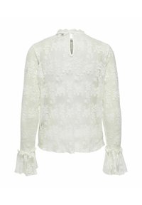 Bílá krajková halenka s dlouhými rukávy, s ozdobnými volánky na manžetách a zapínáním vzadu na klíčovou dírku. Celoplošný květinový vzor s lehkým, texturovaným vzhledem.