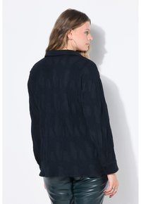 Camicia blu navy scuro con un motivo tessuto e colletto classico. Maniche lunghe con polsini a bottone, realizzata in tessuto leggero.