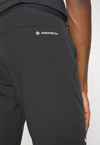 Sorte tights med en tettsittende design, glatt tekstur og et DuraStretch-logo på linningen for økt komfort og fleksibilitet.
