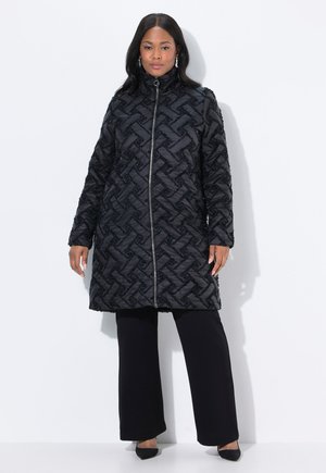 Black quilted coat with a geometric pattern, zip front, high collar, and long sleeves, paired with black wide-leg trousers and heels.