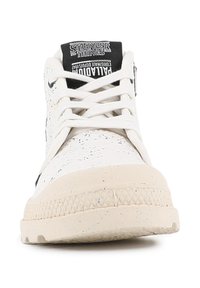 Baskets blanches avec un dessus texturé, semelle en caoutchouc et étiquette de marque noire sur la languette. Comprend des lacets et des accents émaillés sur la semelle.