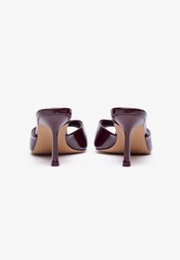 Μπορντό παπούτσια με τακούνι από πατεντέ δέρμα, με ανοιχτή πίσω πλευρά, κομμένο στιλέτο τακούνι και λεία υφή. Μπεζ σόλες ορατές από την πίσω όψη.