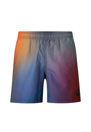 Mężczyzna bez koszulki noszący kąpielówki z gradientem od niebieskiego do czerwonego, czarne klapki i duże żółte sportowe okulary przeciwsłoneczne, stojący na jednolitym tle.