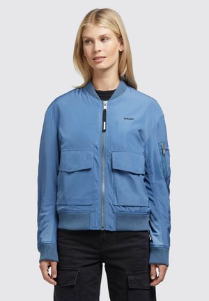 Giacca bomber blu realizzata in tessuto liscio, con due tasche anteriori a pattina e una tasca laterale con zip, maniche e orlo a costine.
