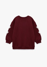 Burgundowa bluza z okrągłym dekoltem, luźnymi rękawami i białymi gwiazdkami na obu rękawach. Wykonana z miękkiego materiału bawełnianego.