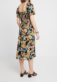 Kwiatowa sukienka do kolan w kolorze czarnym z krótkimi rękawami, z kolorowymi kwiatami i liśćmi, kwadratowym tyłem oraz elastycznym marszczeniem w pasie.