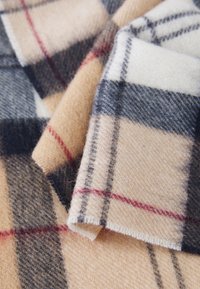 Wollen plaid stof met een beige en crèmekleurige basis, met een ruitpatroon in marineblauw en rood. Zachte textuur met een licht fuzzy uiterlijk.