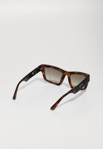Ochelari de soare tortoiseshell maro cu lentile dreptunghiulare, având branding negru îndrăzneț pe brațe și lentile gri cu gradient.