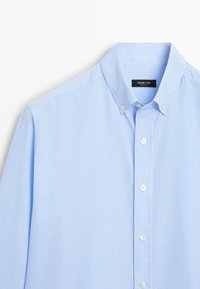 Camicia a righe azzurra chiara con colletto button-down, bottoni bianchi, vestibilità slim e texture in cotone morbido. L'etichetta riporta "Massimo Dutti."