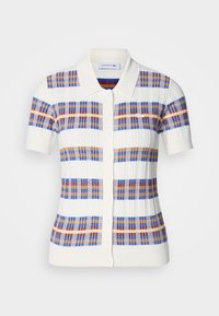 Polo à manches courtes en crème, arborant un motif à carreaux avec des rayures bleues, rouges et brunes, et une fermeture à bouton avec col.