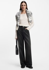 Długie, czarne spodnie o szerokich nogawkach i wysokim stanie, zestawione z jasnokremową bluzką z długim rękawem. Uzupełnione o dzierganą czarno-białą szal.