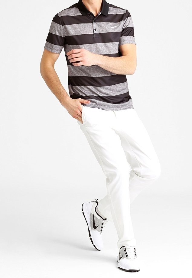 Polo rayé noir et gris avec col, assorti à un pantalon blanc et des chaussures de sport noir et blanc. Logo subtil de Nike sur le polo.