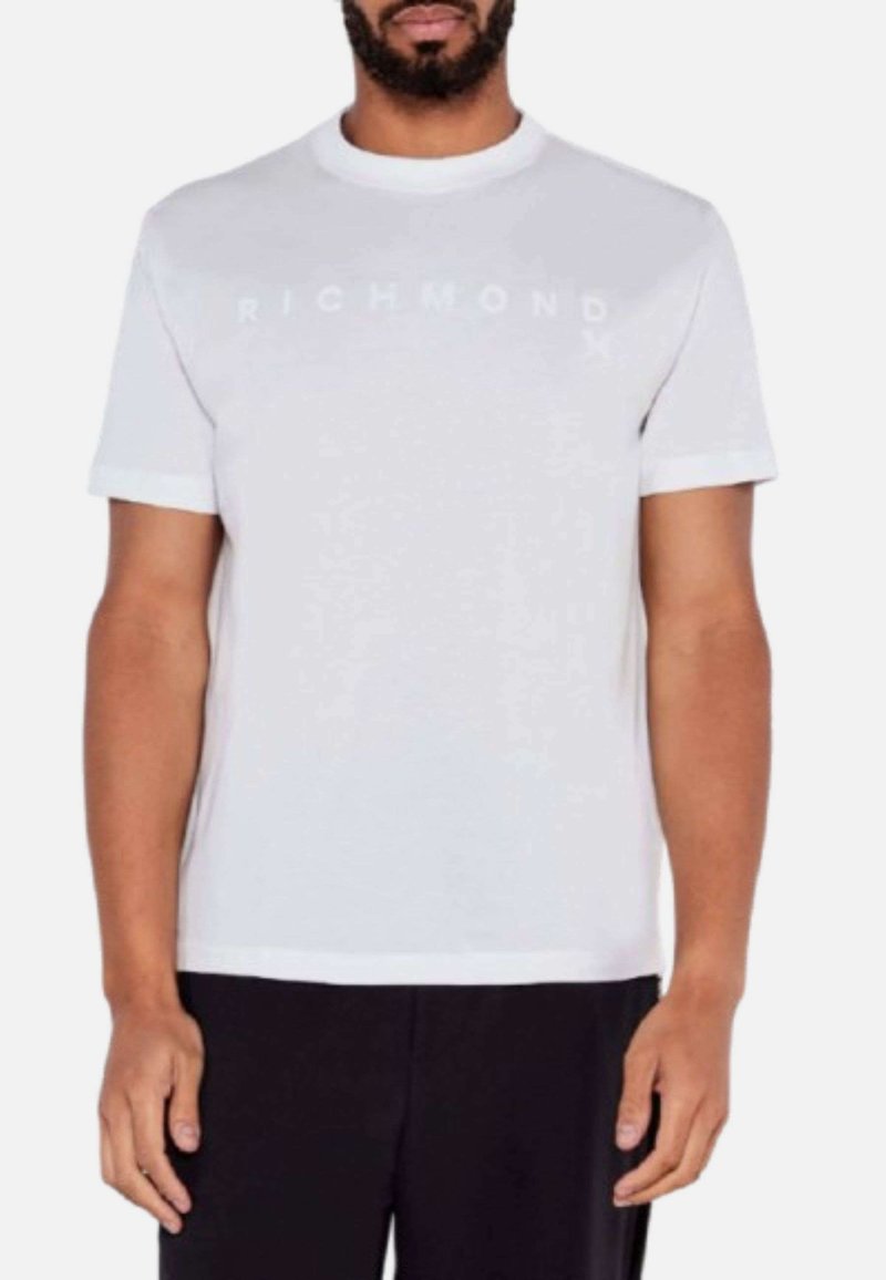 Camiseta blanca de manga corta con una superficie texturizada y "RICHMOND" impreso en letras sutiles a lo largo del pecho. Cuello redondo sencillo.