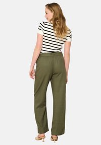 Olive green wide-leg trousers with a relaxed fit, featuring an elastic waistband and a smooth texture. Paired with a striped shirt.