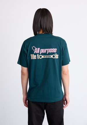Dark teal cotton t-shirt featuring a design on the back with the text "All purpose life to tools" in pink and beige, plus a wrench graphic.