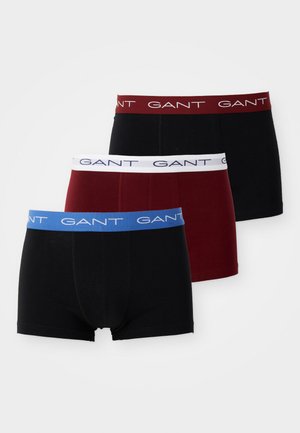 Drie paar boxershorts: zwart, bordeauxrood en blauw met GANT-merk. Zacht katoenmateriaal, met elastische taillebanden in contrasterende kleuren.